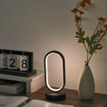 Mini Lámpara de Mesa LED USB Regulable 3 Colores encendida sobre un escritorio de madera