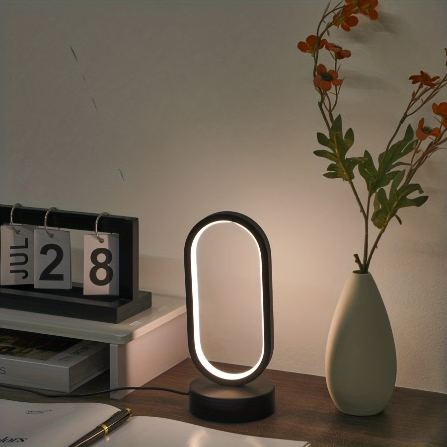 Mini Lámpara de Mesa LED USB Regulable 3 Colores encendida sobre un escritorio de madera