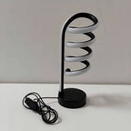 Lámpara de Escritorio LED Espiral Curva Luz Cálida con luz fría encendida en un estudio