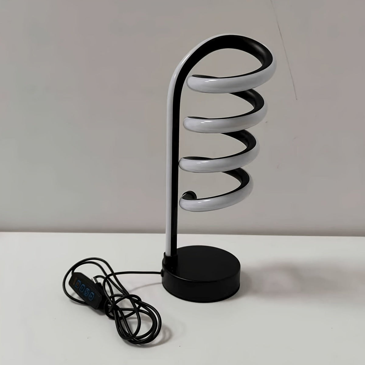 Lámpara de Escritorio LED Espiral Curva Luz Cálida con luz fría encendida en un estudio