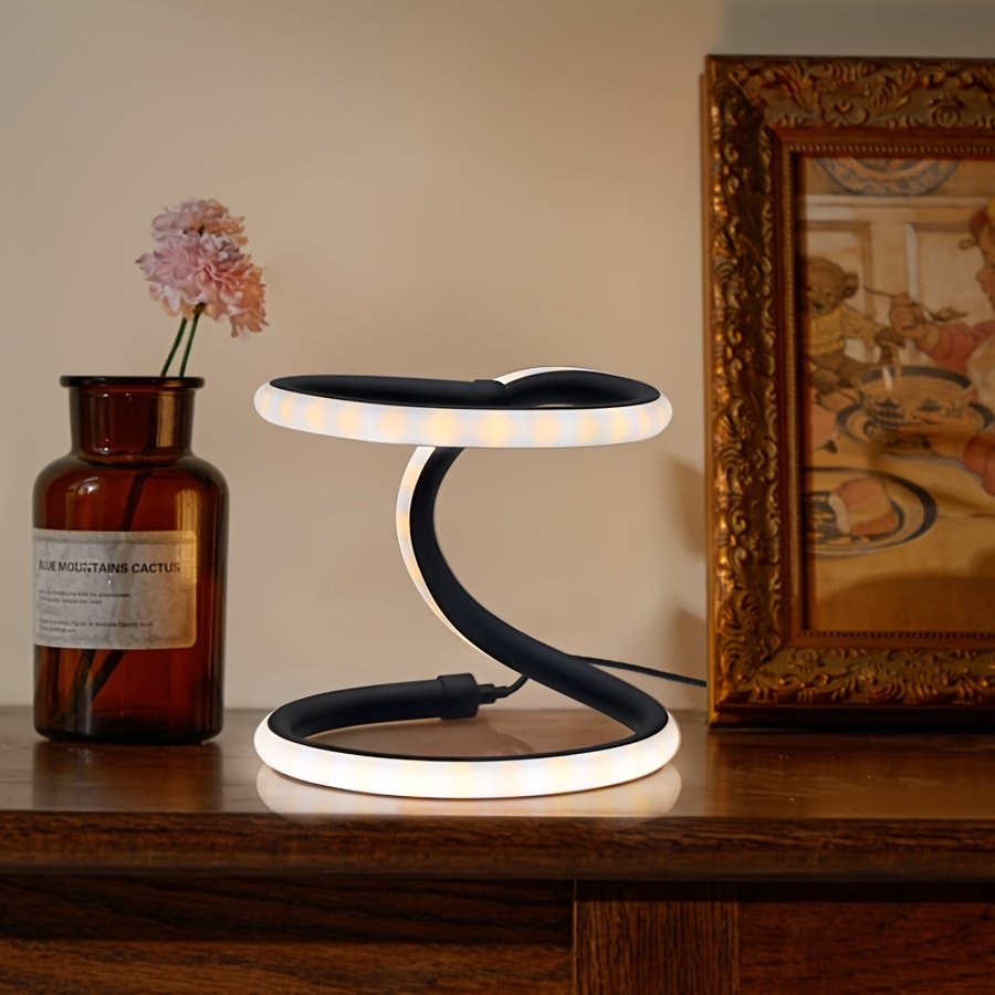 Lámpara de Mesa LED Doble Anillo Infinito Dorada encendida sobre un escritorio de madera